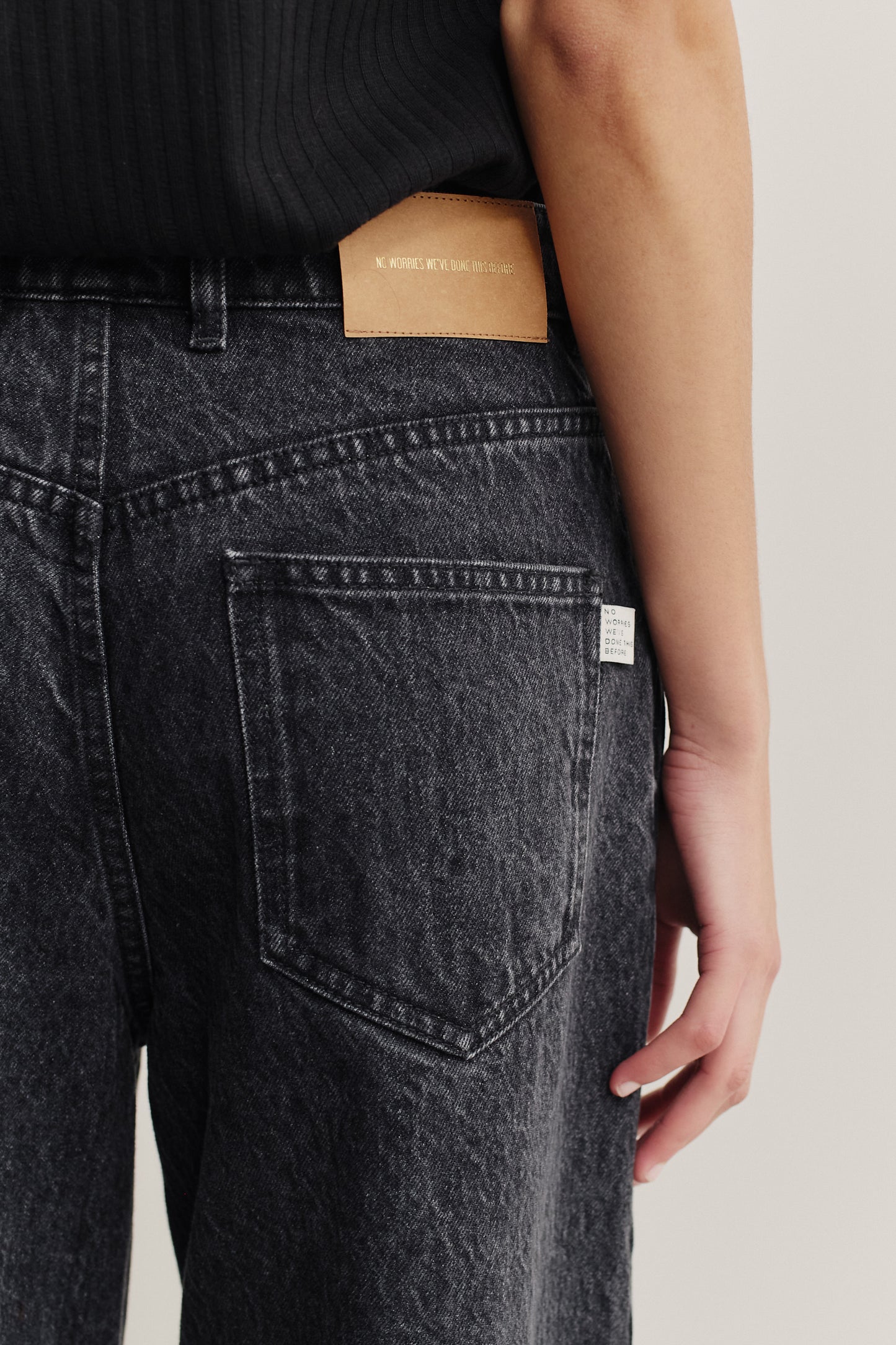 Women's long-pants, organic cotton denim, stone washed, dark grey, with pleat detail and leather patch.