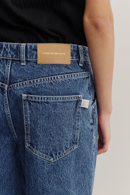 Women's long-pants, cotton mix denim, stone washed, blue. Features a brown leather patch and back pocket.