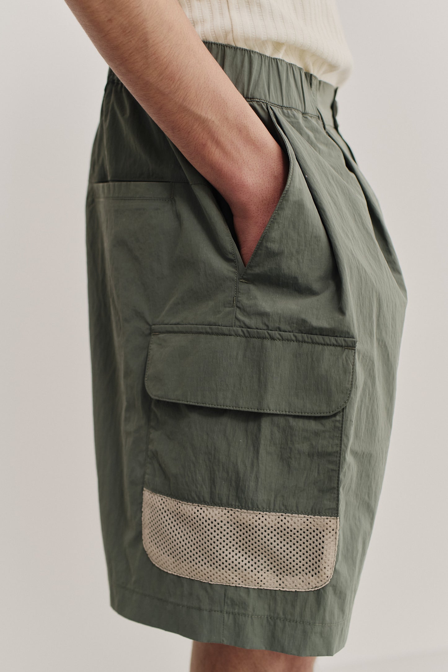 Men's shorts, recycled nylon and cotton blend, water-repellent, olive green, with side patch pockets and mesh detail.