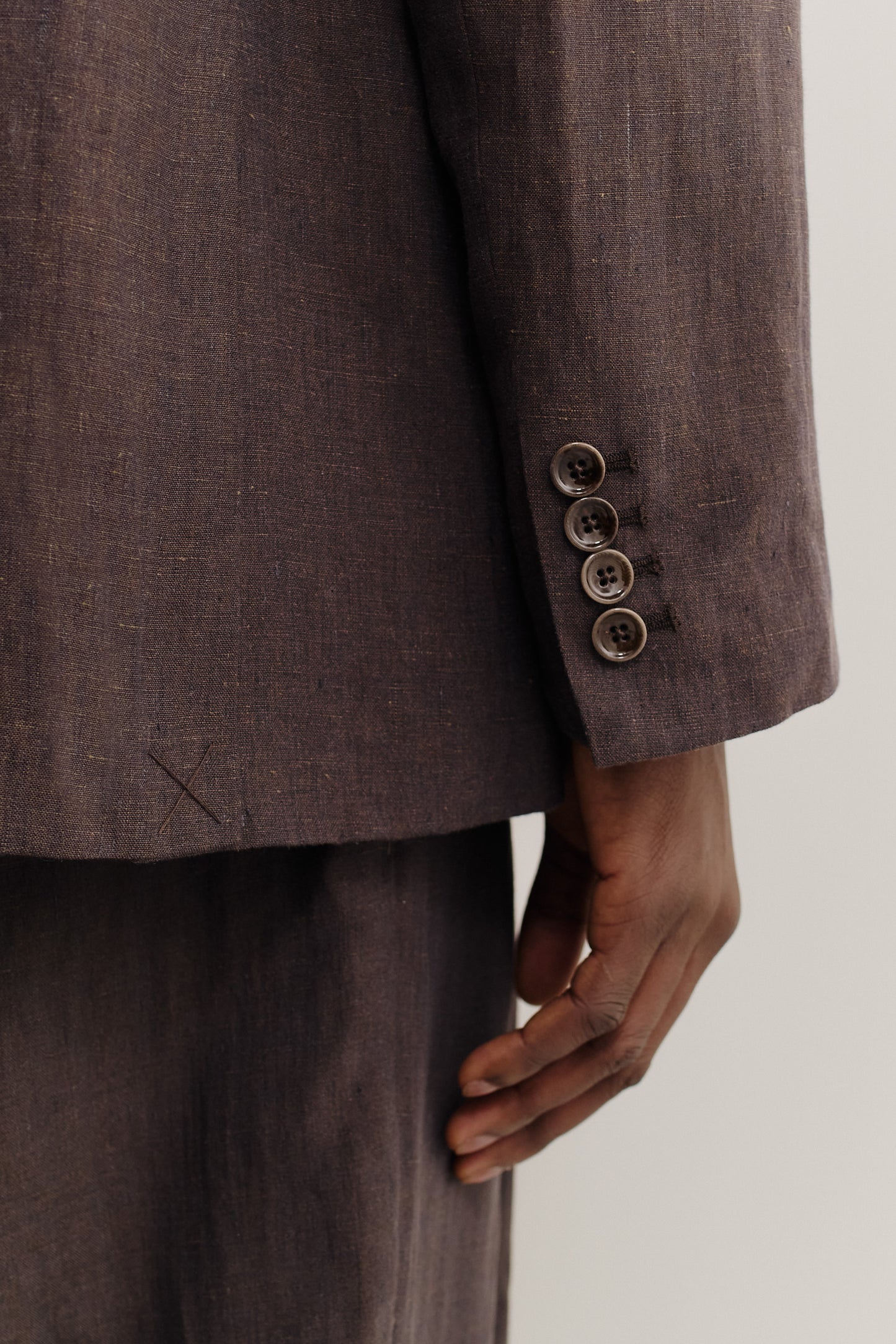Men's tailoring, relaxed double-buttoned blazer, 100% linen, burnt umber, with four dark buttons on the sleeve.