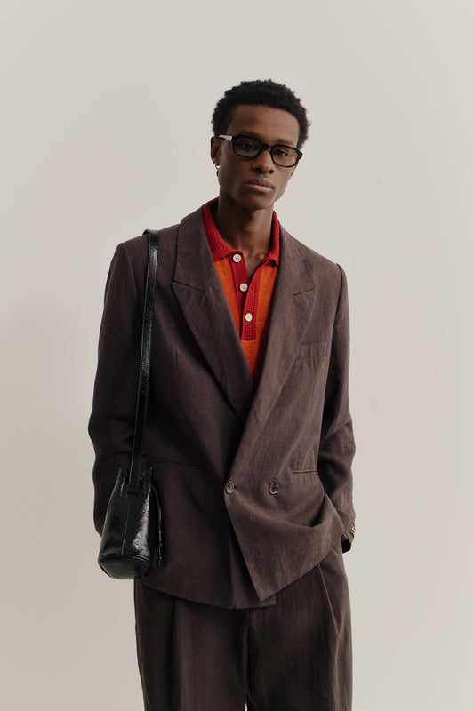 Men's tailoring, relaxed double-buttoned linen blazer in burnt umber, paired with a red knit polo.