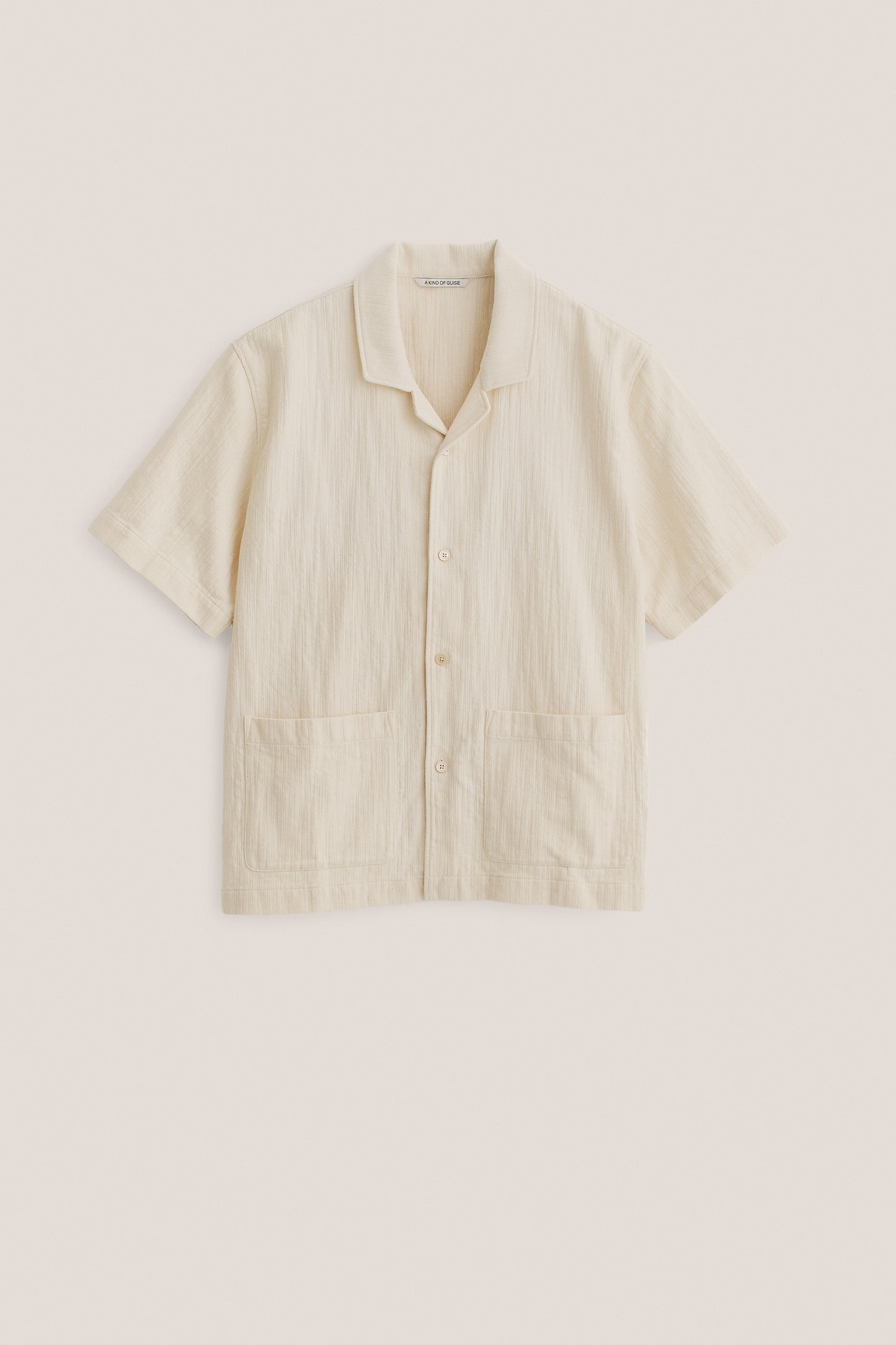 Men's short-sleeved shirt in textured recycled cotton mix, plain off-white, with spread collar and double patch pockets.
