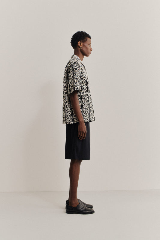 Men's short-sleeved shirt, 100% cotton, black with white embroidered flower blocks, notched collar, relaxed fit.