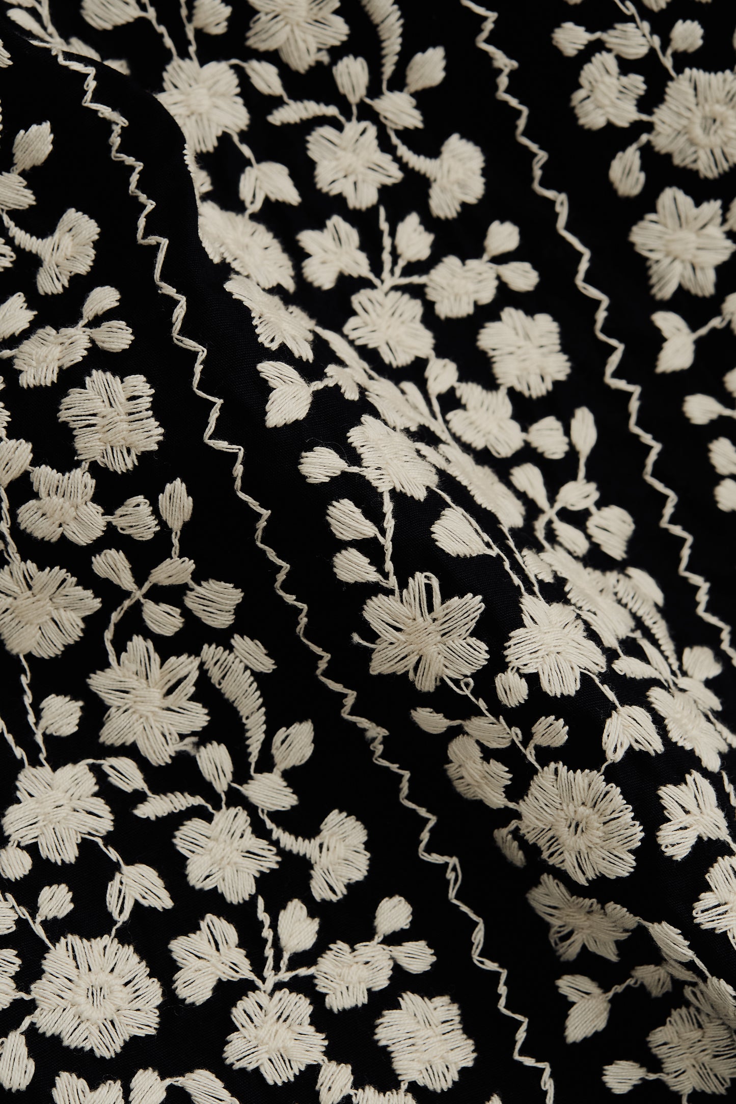 Men's short-sleeved shirt, 100% cotton, black with white embroidered floral blocks and wavy lines.