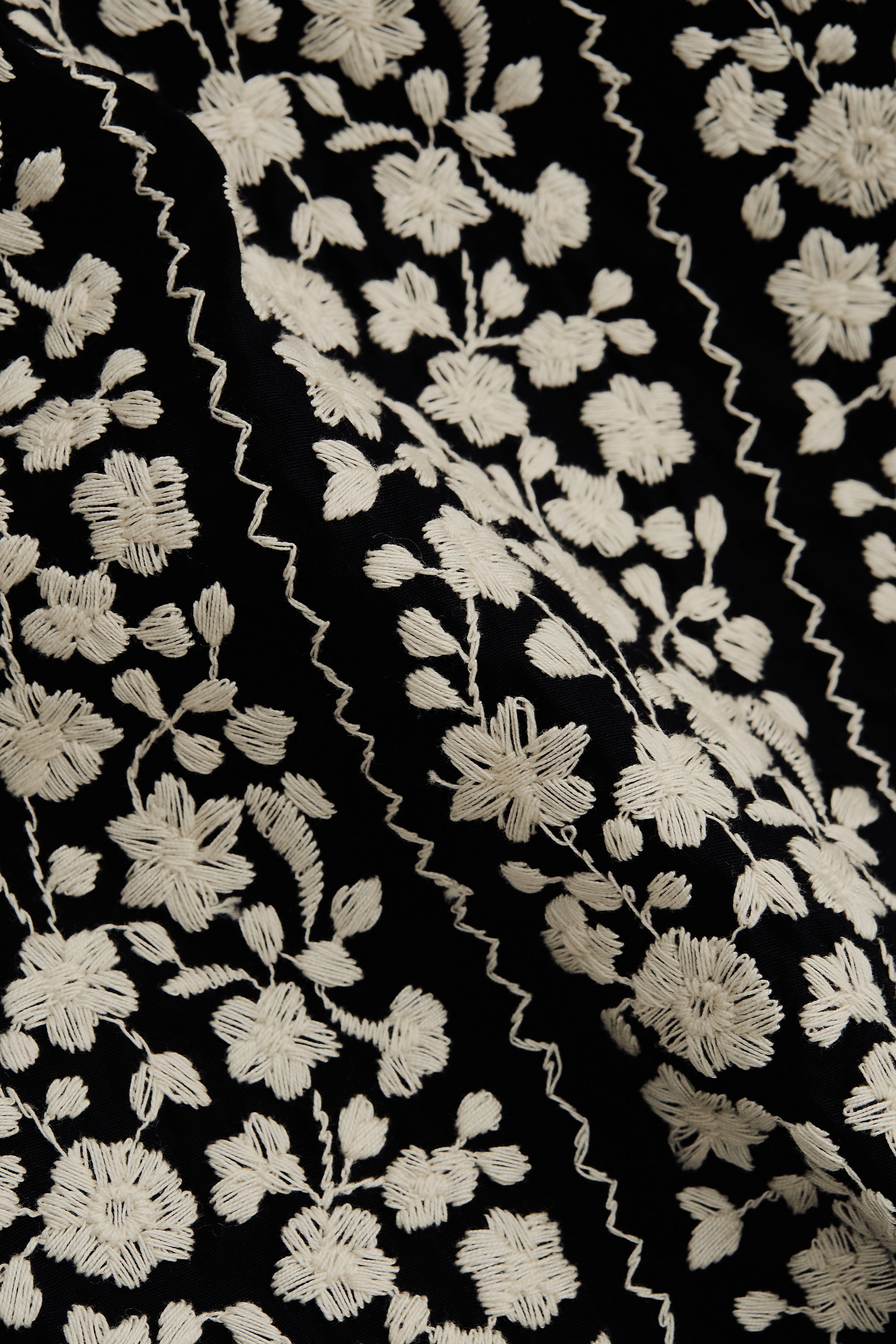 Men's short-sleeved shirt, 100% cotton, black with white embroidered floral blocks and wavy lines.