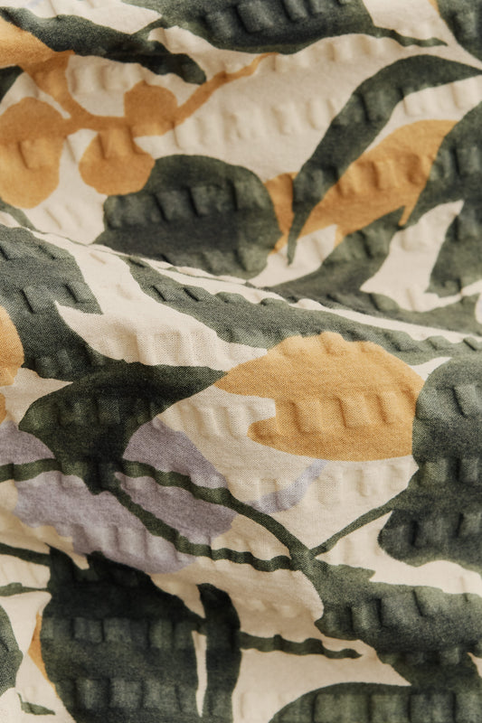 Men's short-sleeved shirt in Japanese cotton seersucker with a beige, green, and yellow floral pattern.