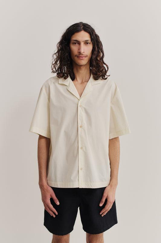 Men's short-sleeved shirt, organic cotton, garment washed, off-white, with notched collar and dropped shoulders.