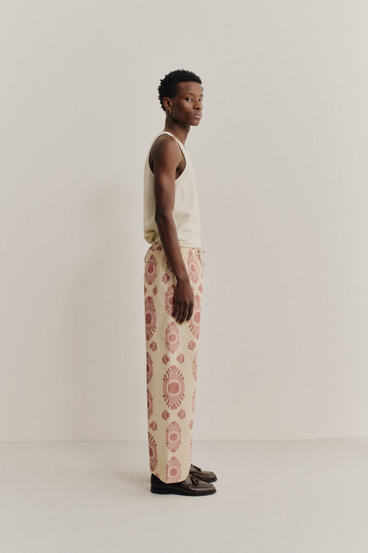 Men's long-pants, cotton and recycled polyester blend, ikat print, beige with red pattern.