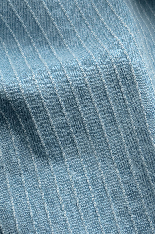 Men's pants, organic cotton light blue denim with subtle white pinstripes, washed finish.
