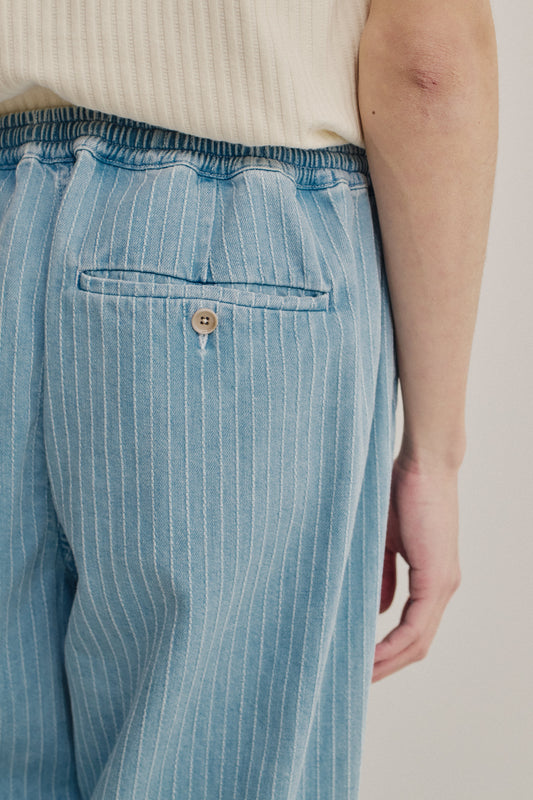 Men's long-pants, organic cotton denim, washed light blue with white pinstripes, elastic waist, and buttoned back welt pocket.