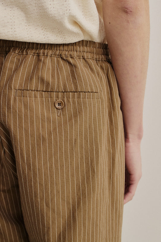Men's long-pants, cotton-linen seersucker, brown with white pinstripes, elastic waist, and buttoned back welt pocket.