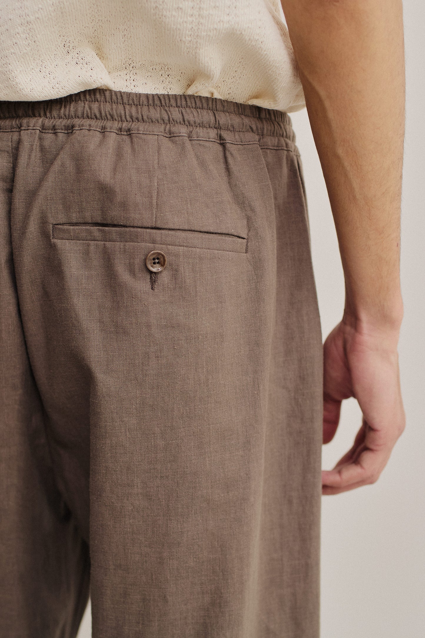 Men's long-pants, 100% linen, natural brown, with elasticated waistband and buttoned welt back pocket.