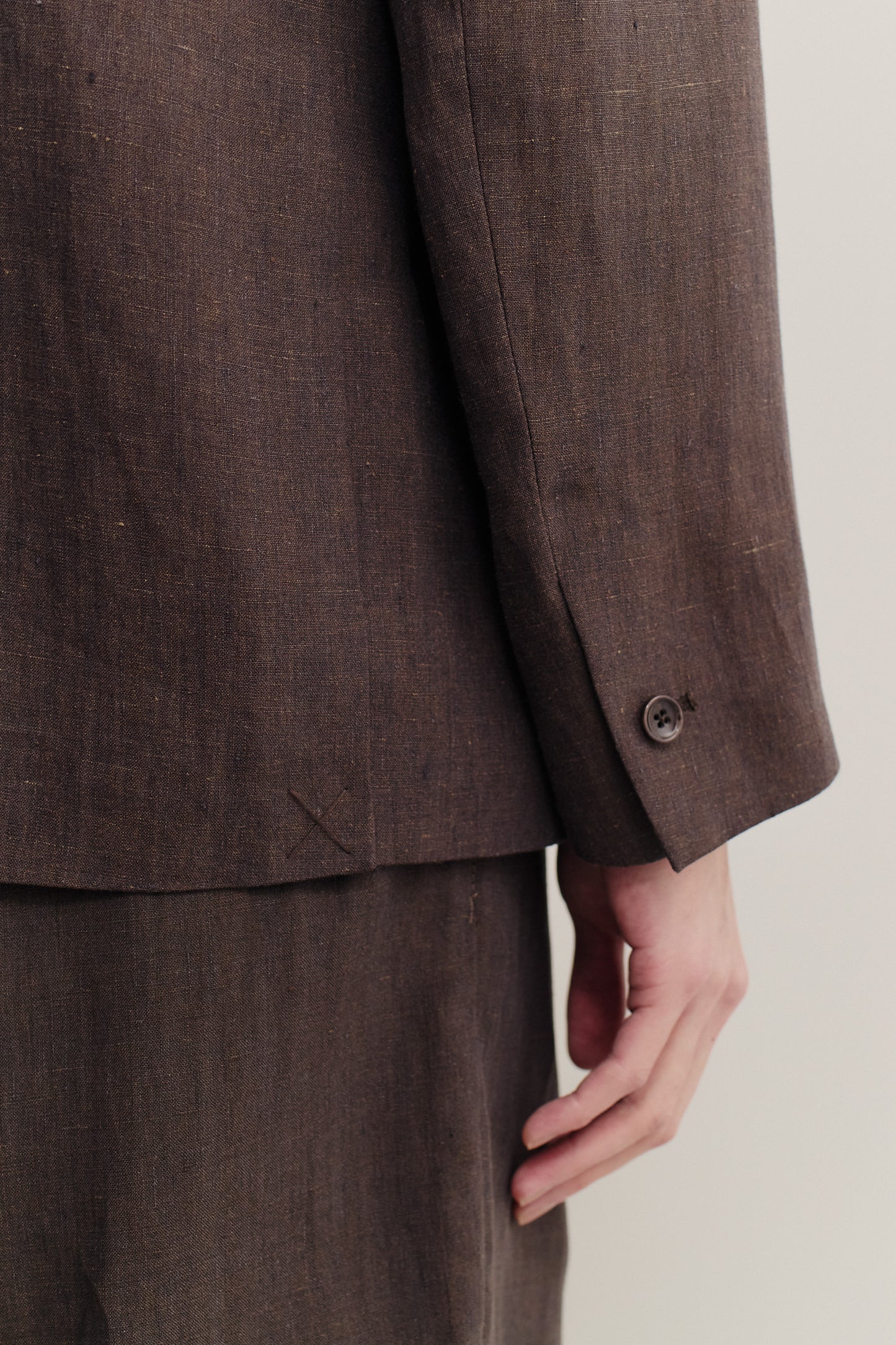Men's tailoring blazer, 100% linen, burnt umber, with buttoned sleeve cuff and subtle surface effect.
