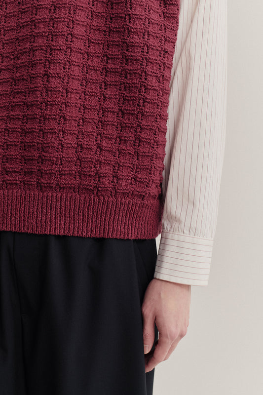 Men's knit vest, cotton-wool bouclé, openwork knit, burgundy, worn over striped shirt.