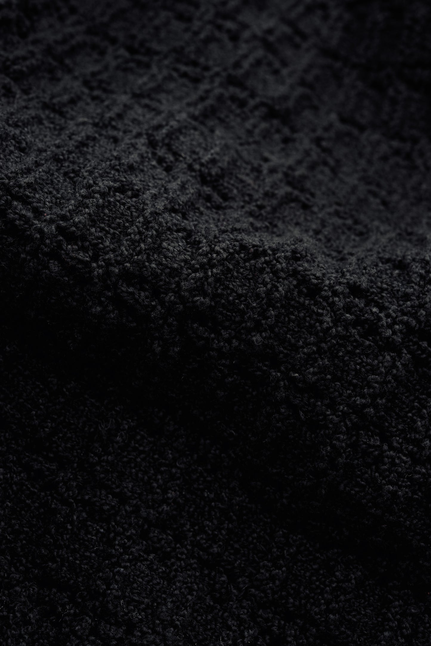 Men's knit vest, black organic cotton-wool bouclé with openwork knit pattern, tactile surface.