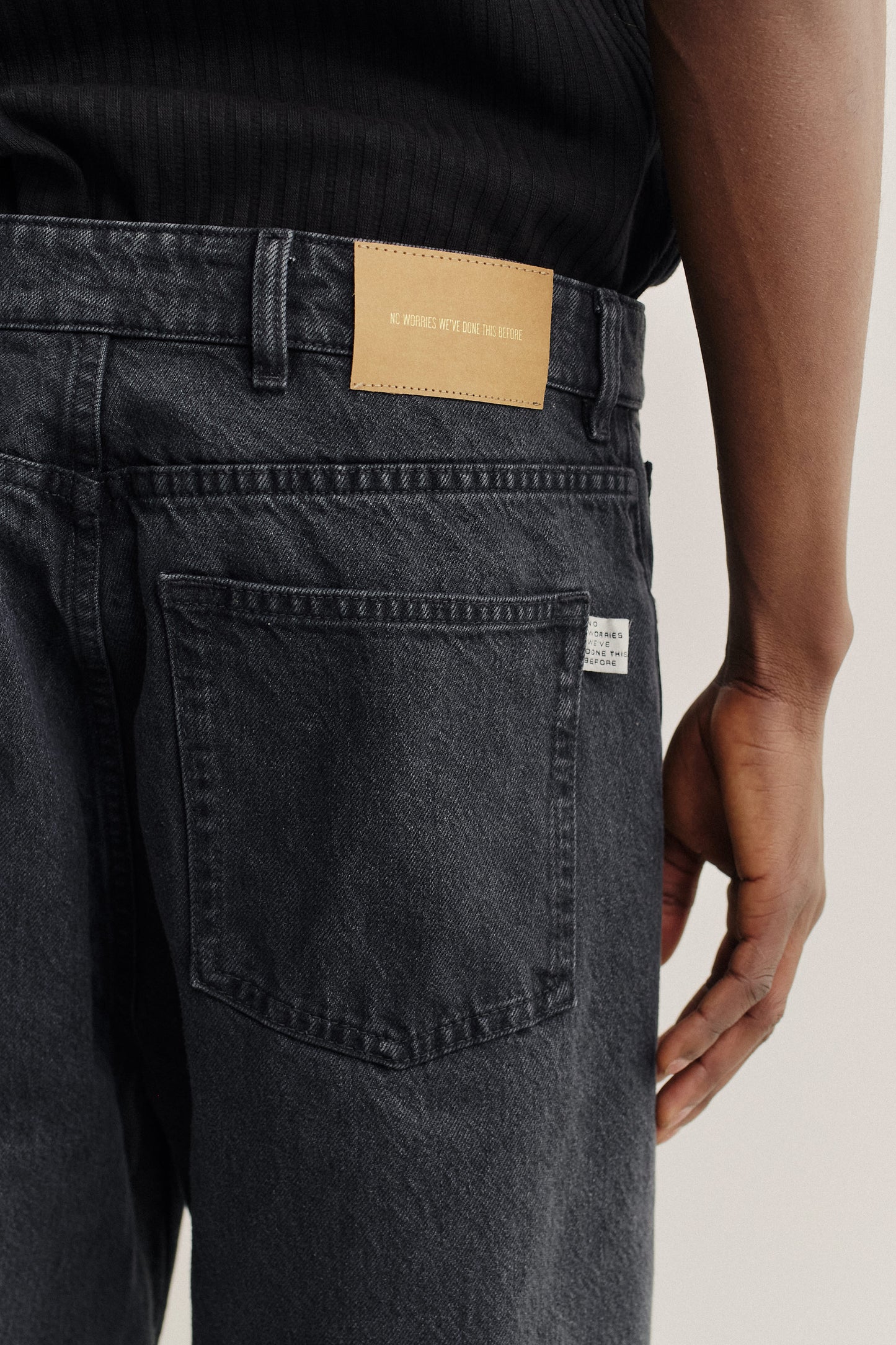 Men's long-pants, organic cotton, stone washed, dark grey denim jeans with a brown leather patch.