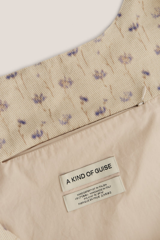 Women's accessories bag, cotton-linen blend twill with ecru base, subtle lilac/brown floral print, visible diagonal twill lines.