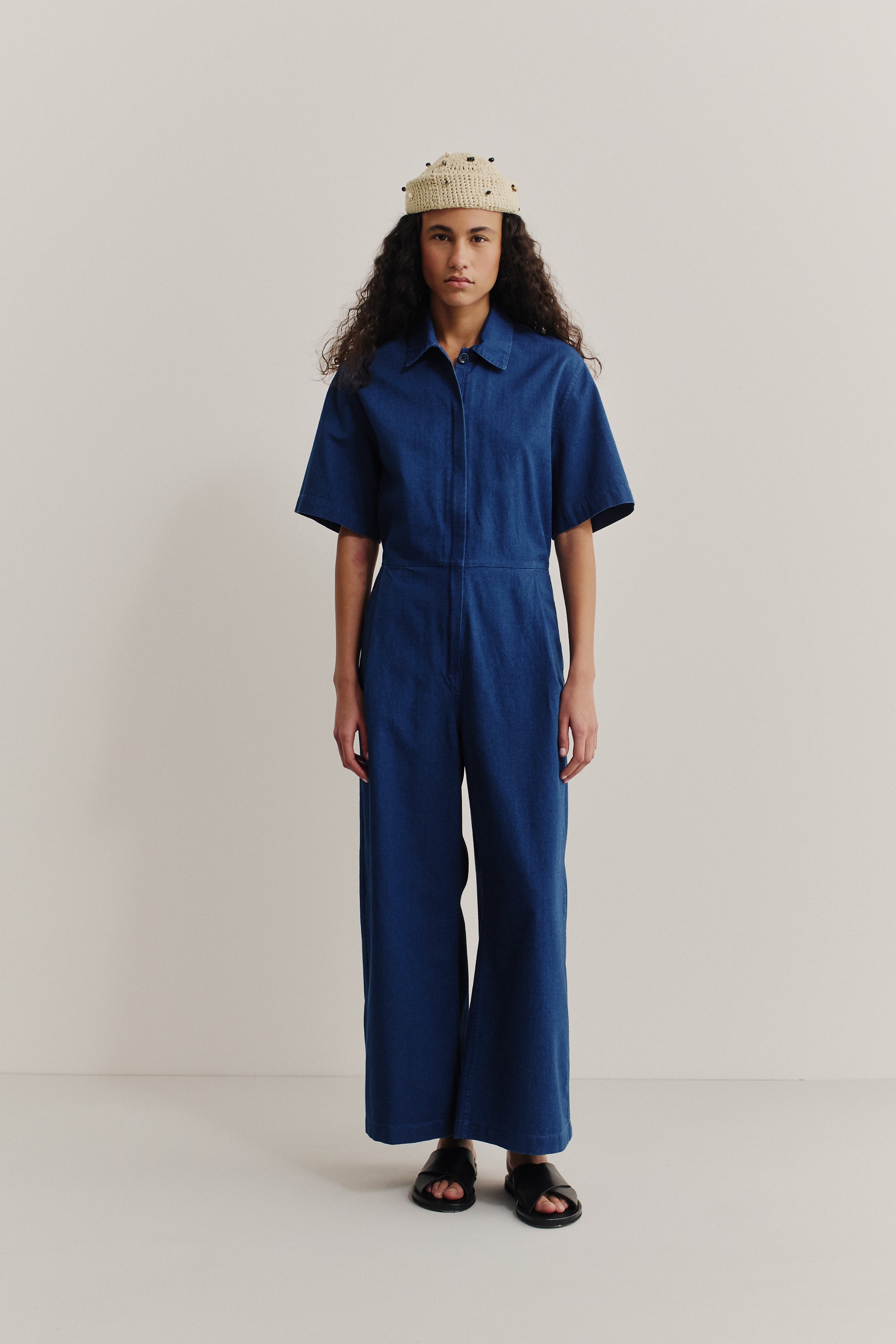 Women's short-sleeved jumpsuit, washed indigo cotton, with a lay-down collar, adjustable waistband, and wide legs.