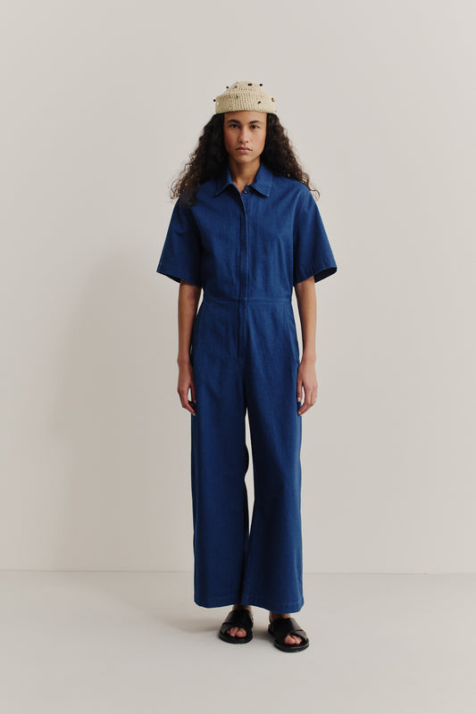 Women's short-sleeved jumpsuit, washed indigo cotton, with a lay-down collar, adjustable waistband, and wide legs.