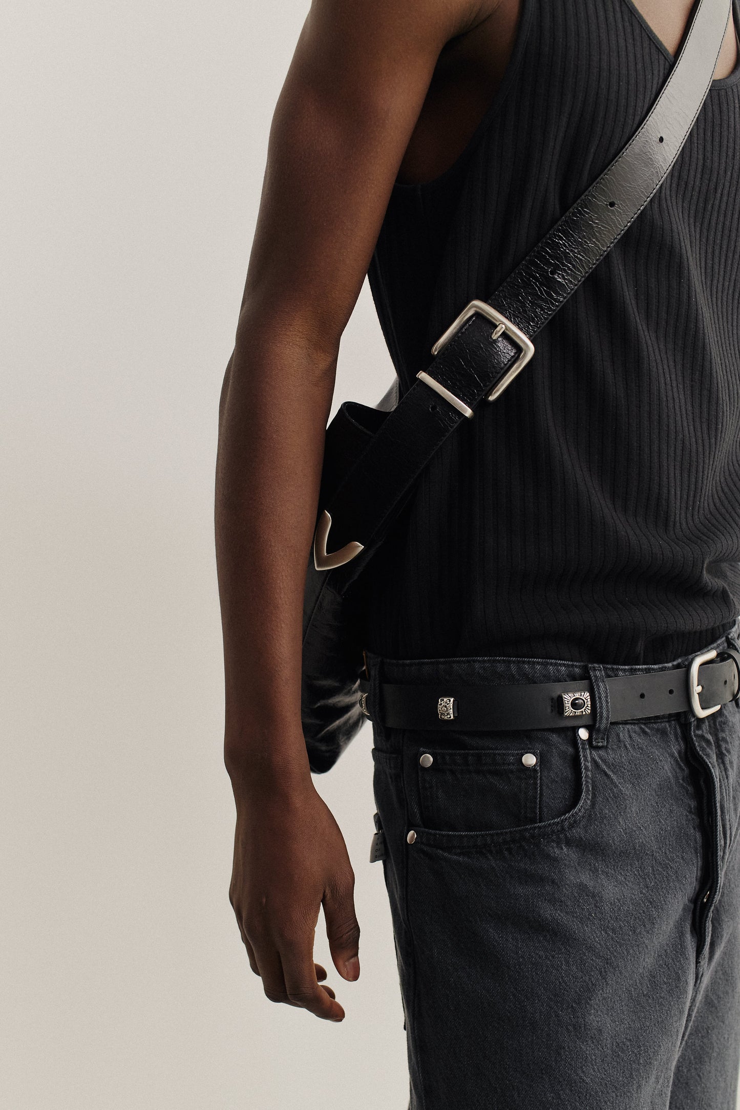 Men's accessories, black LWG-Certified calf leather messenger bag with adjustable belt buckle strap, worn crossbody.