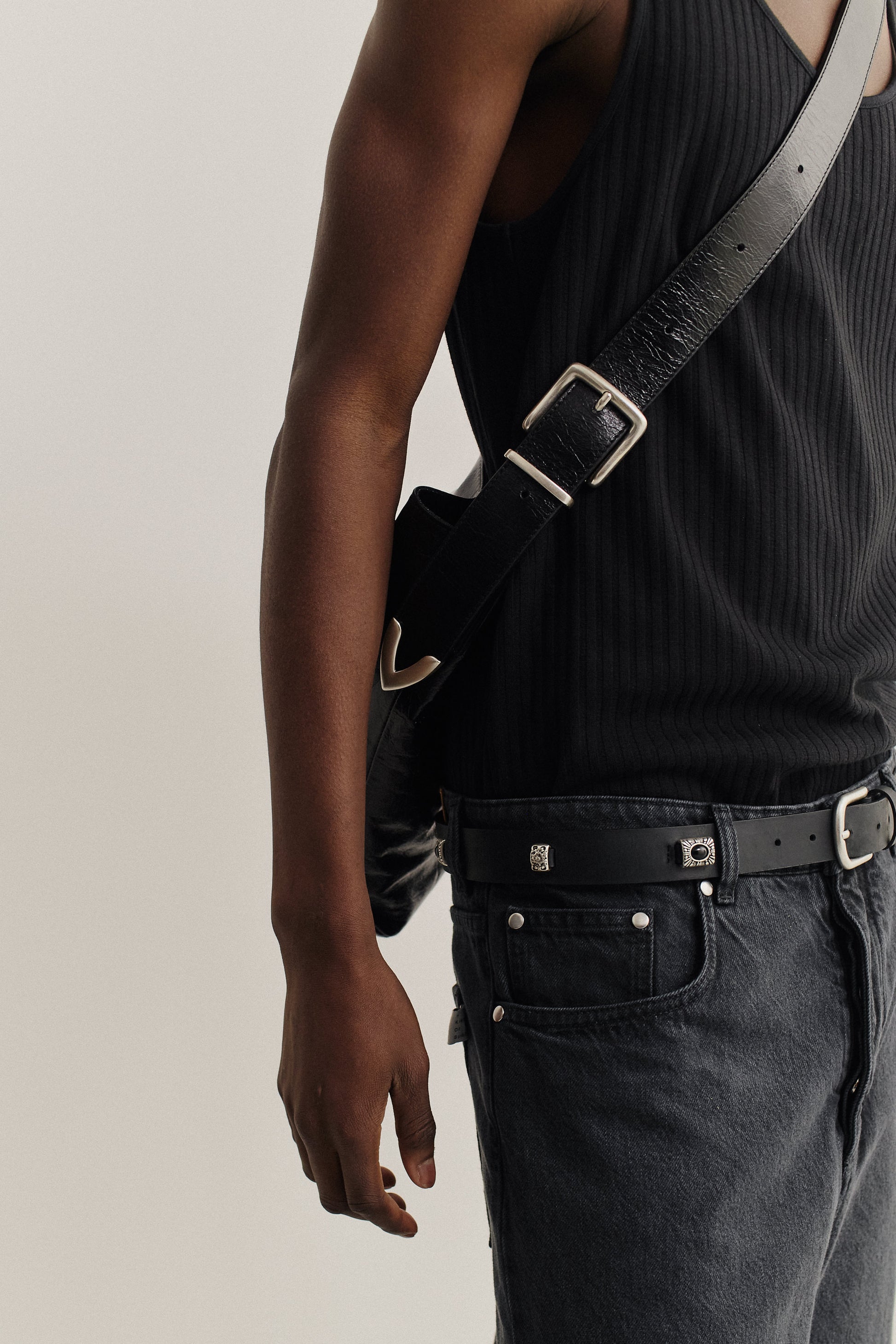 Men's accessories, black LWG-Certified calf leather messenger bag with adjustable belt buckle strap, worn crossbody.
