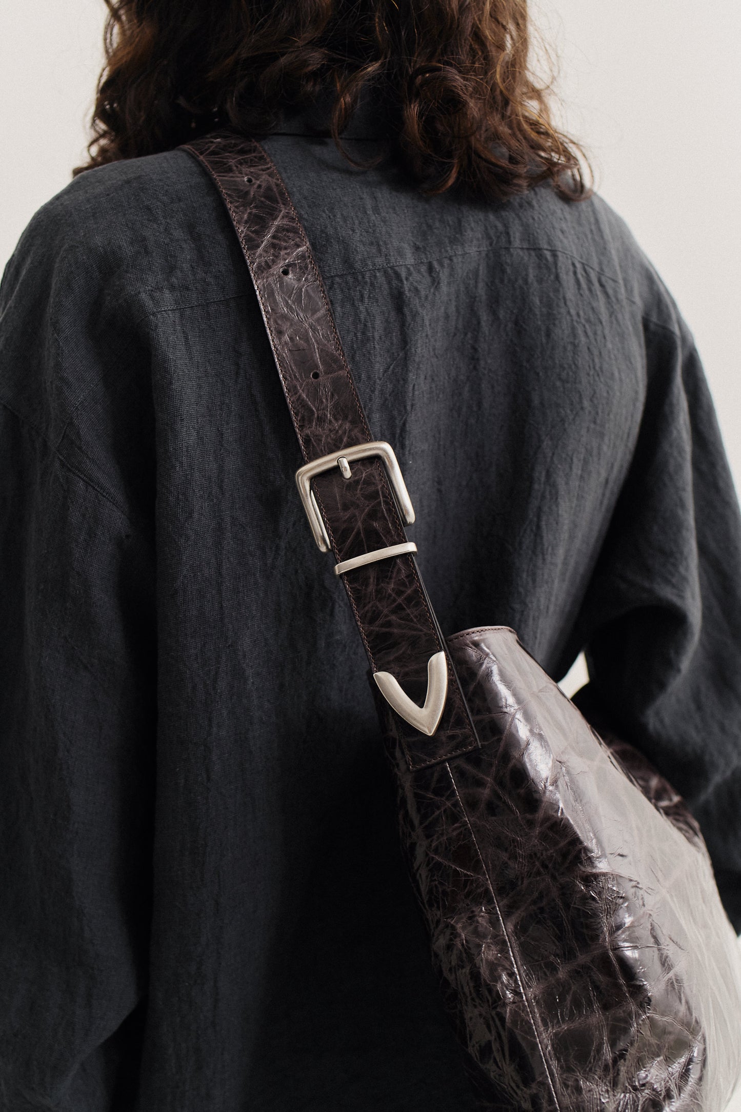 Unisex accessories messenger bag, LWG-certified calf leather, naturally creased, glossy dark brown with silver buckle.