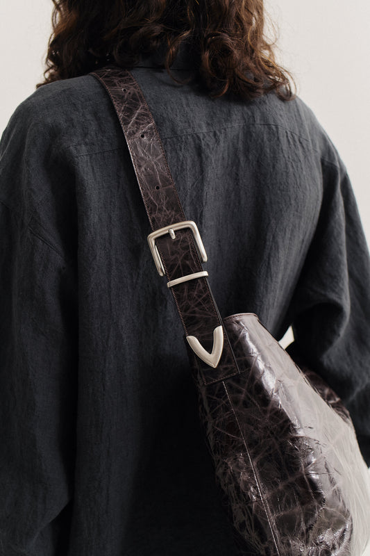 Unisex accessories messenger bag, LWG-certified calf leather, naturally creased, glossy dark brown with silver buckle.
