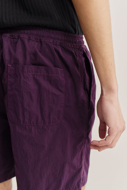 Men's shorts, recycled polyamide, garment-dyed purple, with elastic waist and back patch pocket.
