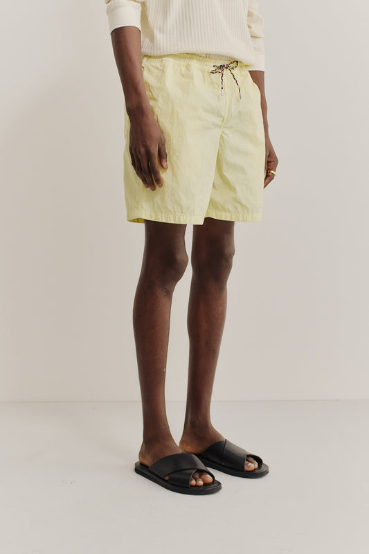 Men's shorts, recycled polyamide, garment-dyed light yellow, with pull cords and side pockets.