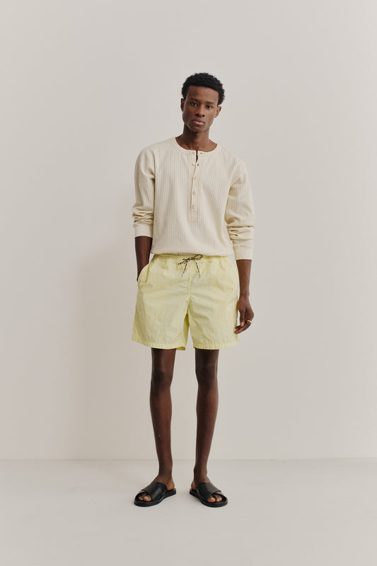 Men's shorts, recycled polyamide, garment-dyed washed light yellow, with black drawstring.