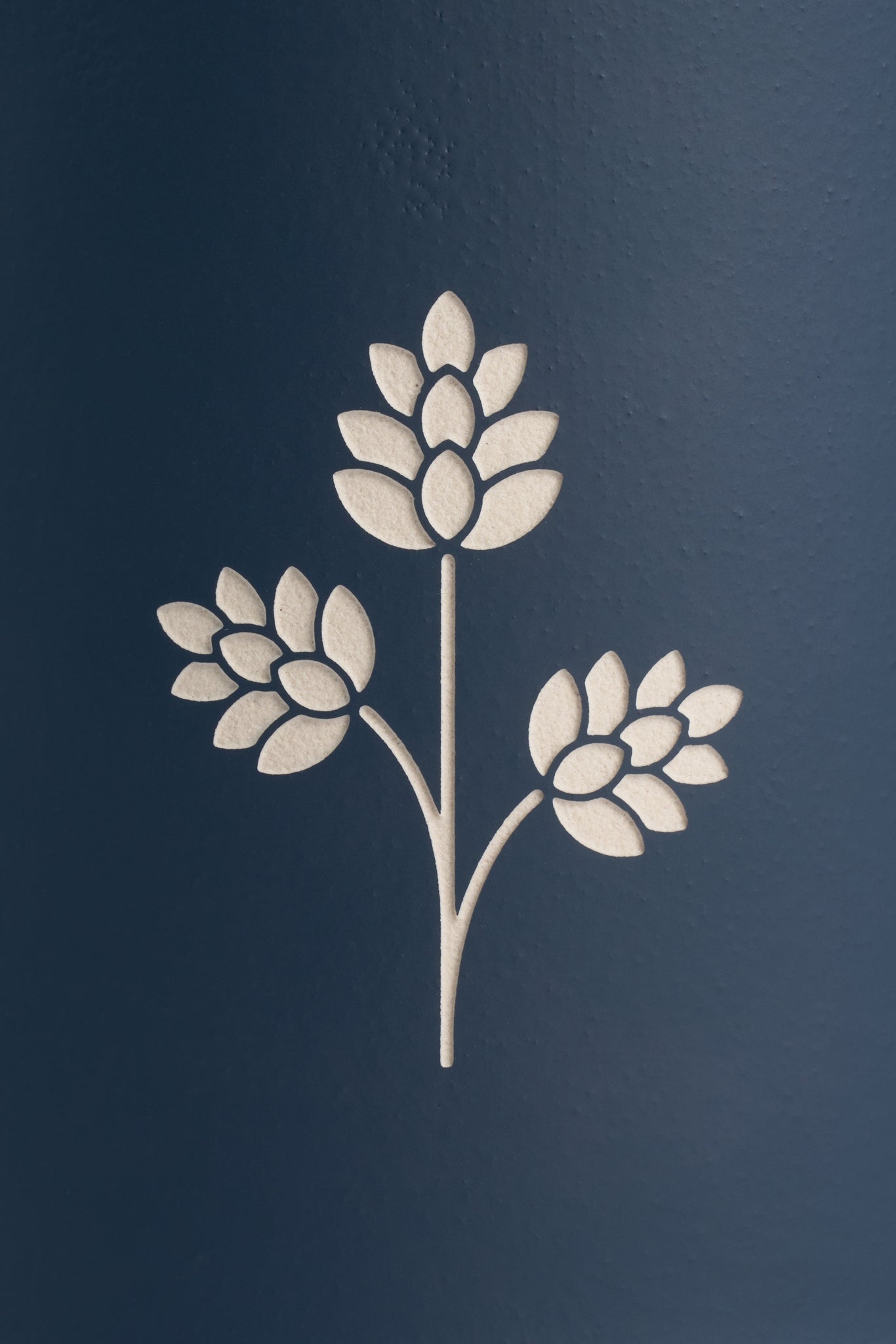 White engraved hop plant detail on a dark blue stoneware beer mug.