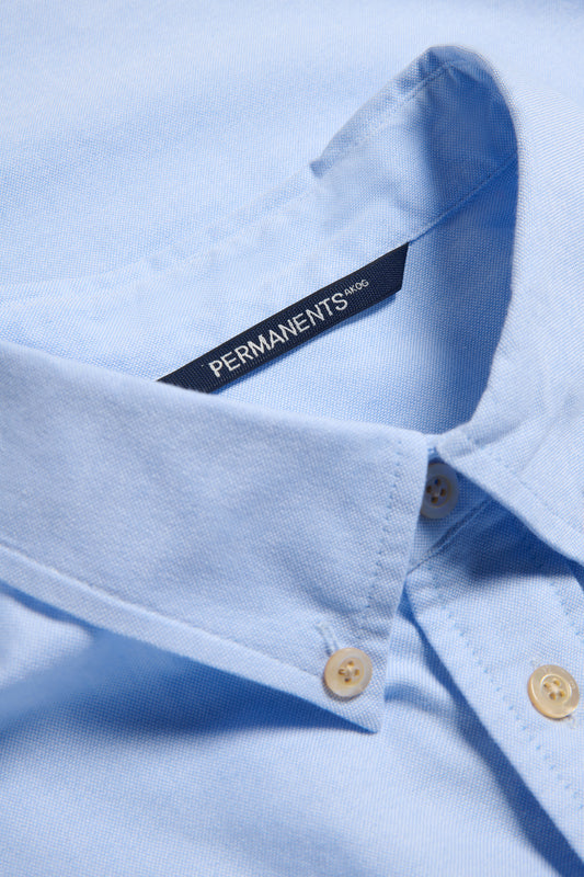 Men's long-sleeved shirt, light blue organic cotton, with pearl buttons and "PERMANENTS" label.
