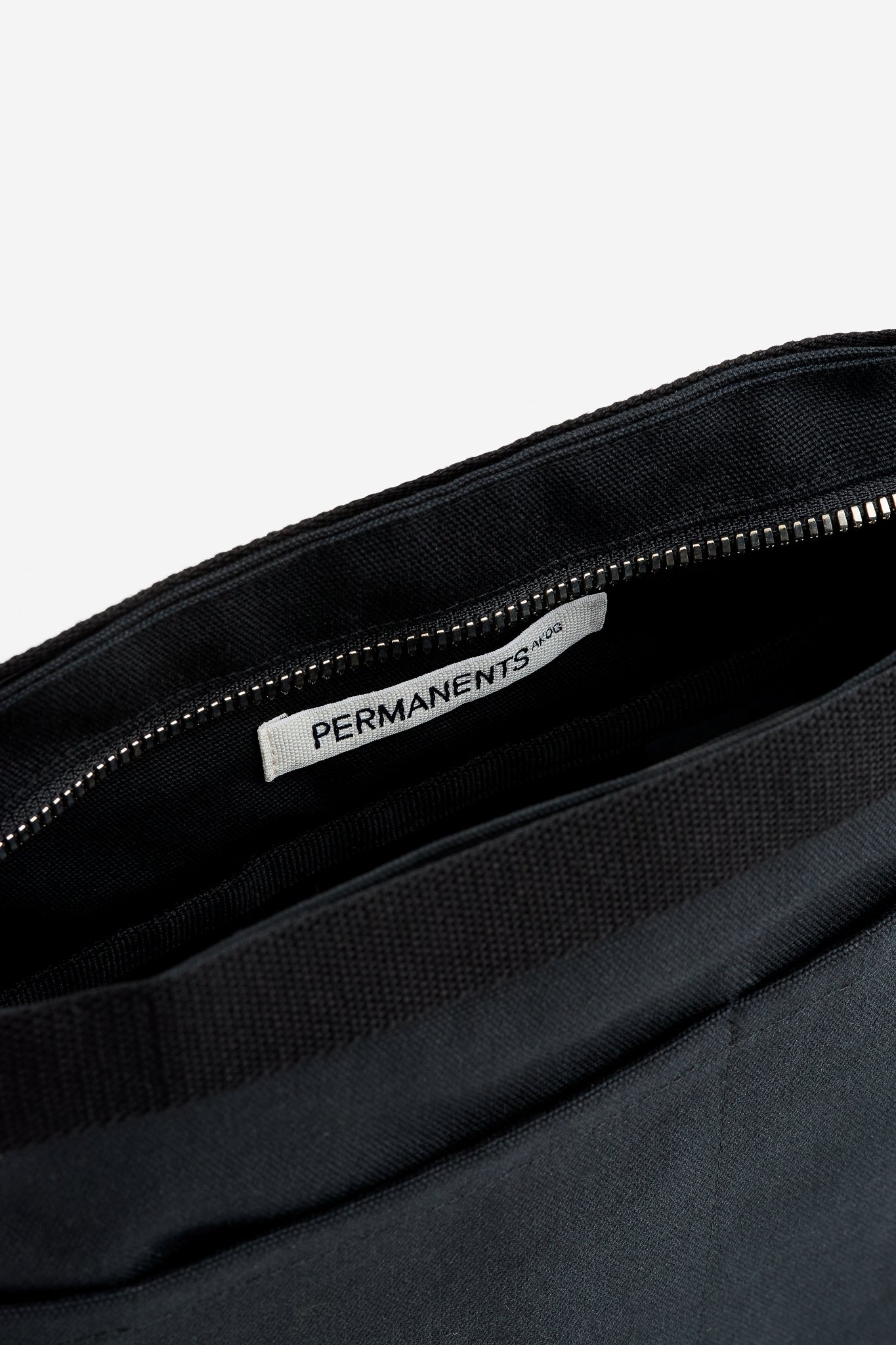 Unisex accessories bag, recycled Ventile® cotton, black, with visible zipper and "PERMANENTS" label inside.